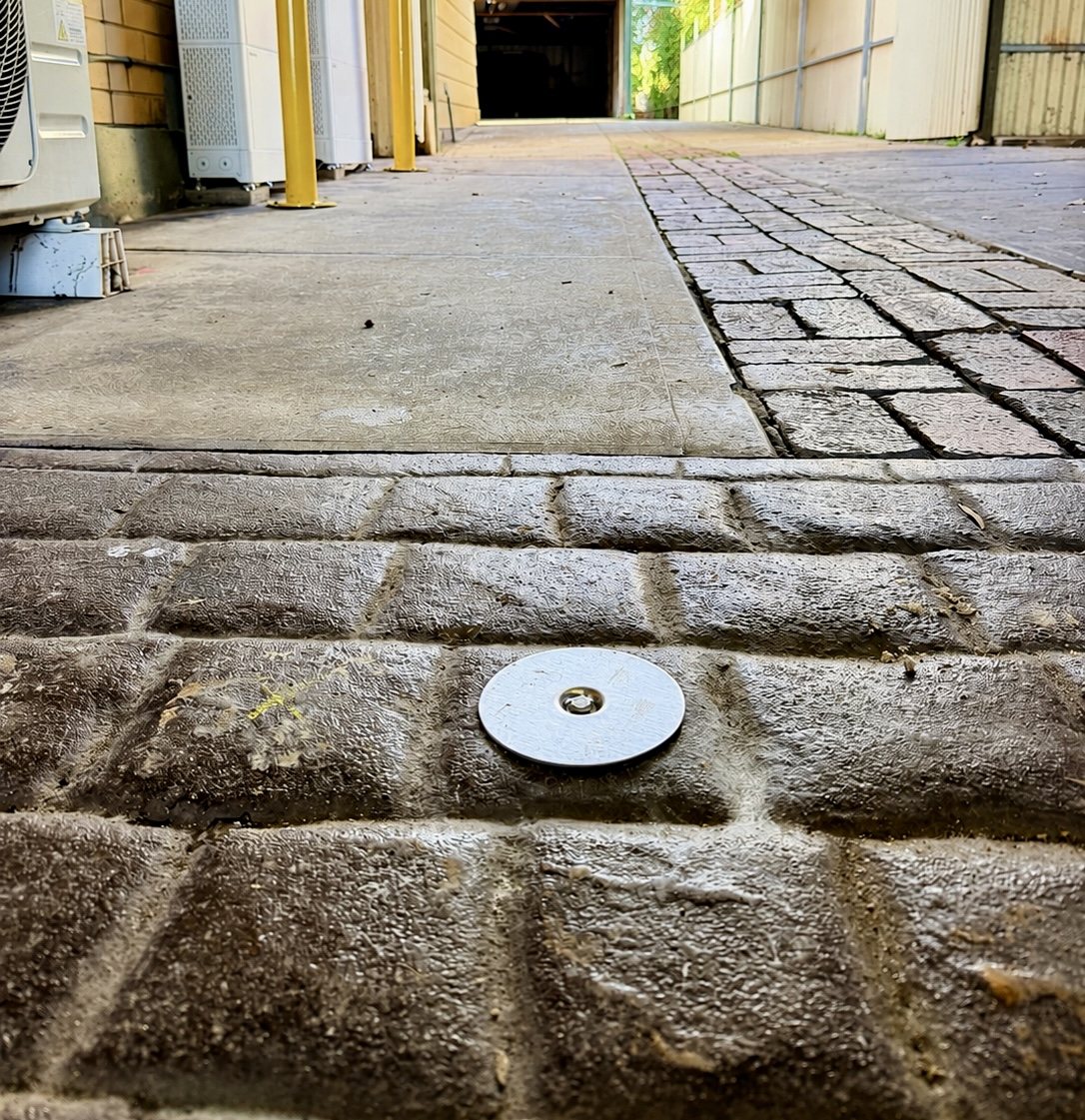 Circular access point fitted into outdoor paving for termite station or monitoring access